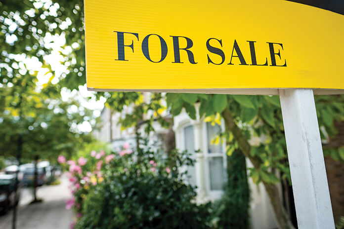 A for sale sign outside a house on a street